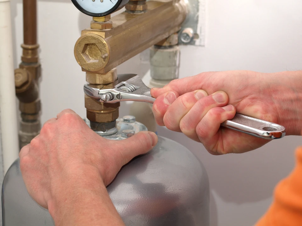 Plombier effectuant une réparation sur installation de chauffage dans un local technique