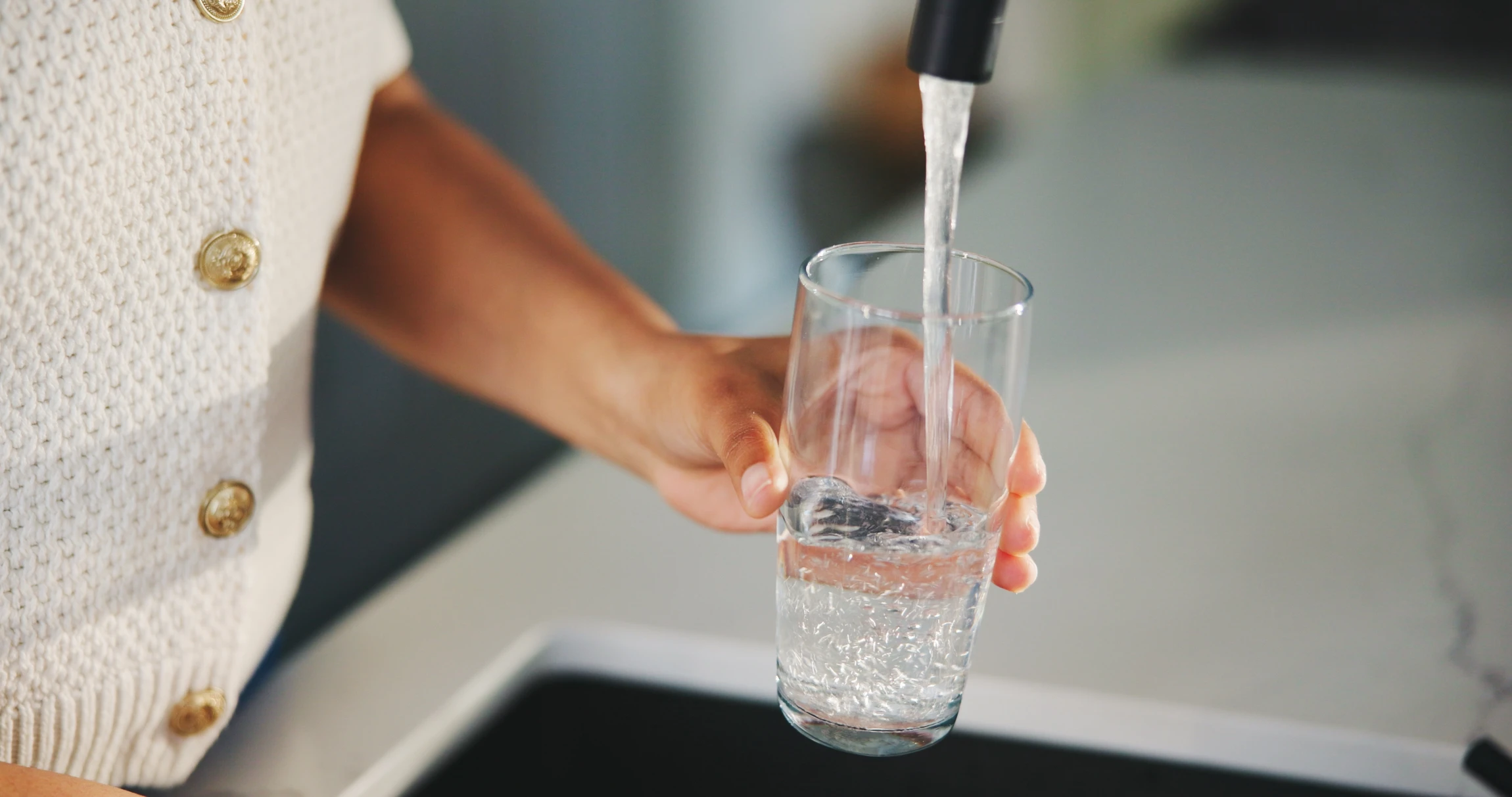 Technicien en combinaison bleue installant un système de filtration d'eau sous évier de cuisine moderne