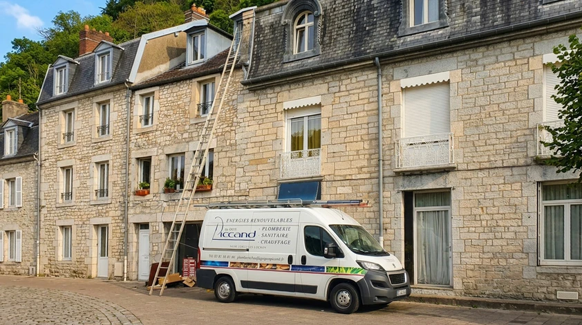 Une main tient une clé à molette pour serrer un raccord de plomberie sur des canalisations cuivre